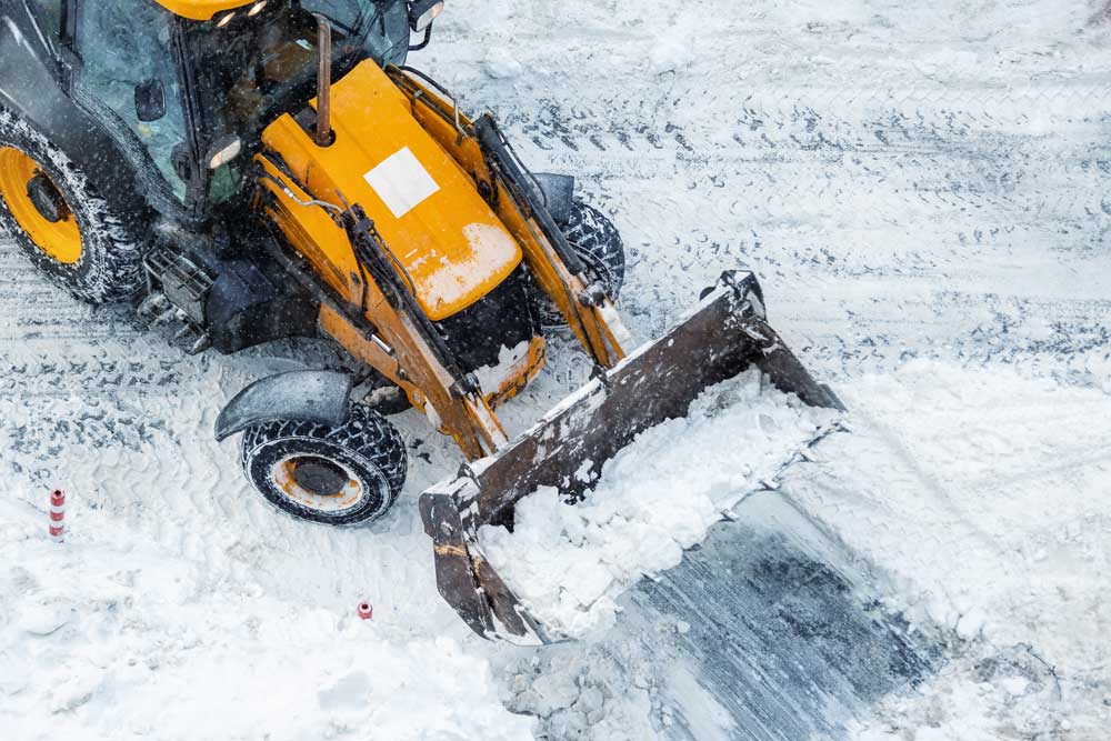 Snowplow truck clearing snow and ice during a professional snow removal service